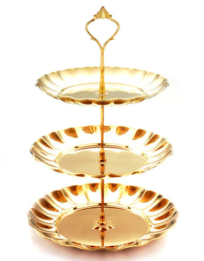 Three-tiered gold cake stand on a white background